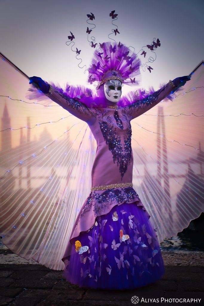On this picture, you can see a woman wearing a lilac costume in the Carnival of Venice in 2020. Her accessory is a lilac transparent pleated cape.