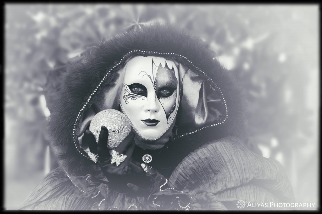Carnival in Venice black and white picture showing a woman wearing a venetian mask .